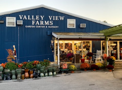 Exterior of Valley View Farms garden center, featuring colorful flowers, pots, and a welcoming entrance.