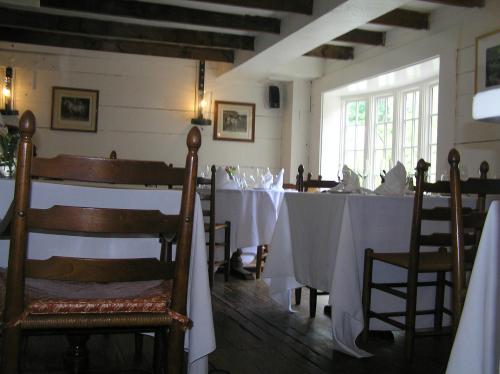 A cozy restaurant interior with wooden chairs and tables set with white tablecloths, featuring soft lighting and rustic decor.