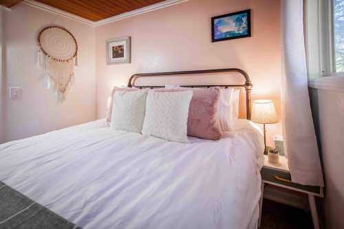 Cozy bedroom with a bed, decorative pillows, a dreamcatcher, and soft lighting from bedside lamps.