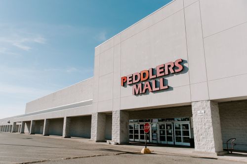 Exterior of Peddlers Mall with a clear blue sky and a "STOP" sign in the parking lot.