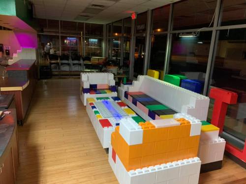 A colorful sofa made of large building blocks in a brightly lit, empty restaurant interior.