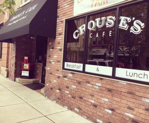 Exterior of Crouse's Cafe, featuring a sign for breakfast and lunch, with a brick facade and awning.
