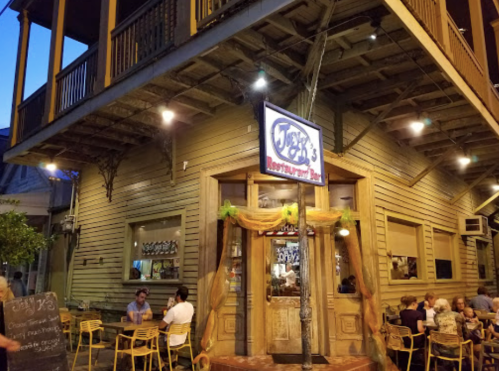 A cozy restaurant exterior with a sign reading "Joey's," featuring outdoor seating and warm evening lighting.