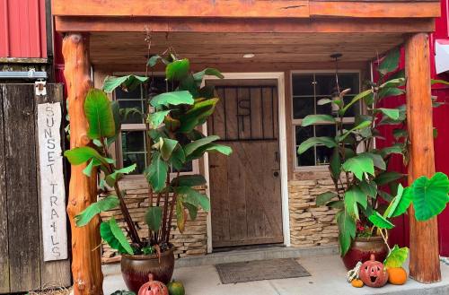 A rustic entrance with wooden pillars, stone accents, and potted plants, featuring a sign that reads "Sunset Trails."