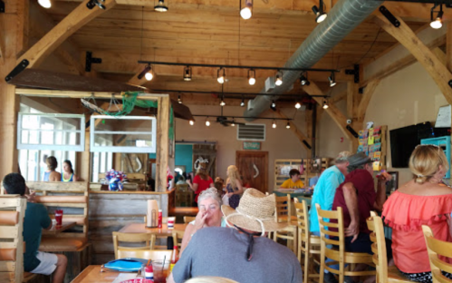 A lively restaurant interior with wooden decor, patrons dining, and a bright, casual atmosphere.