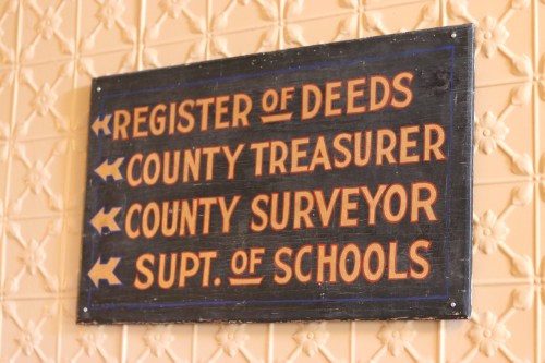 Sign indicating directions to various offices: Register of Deeds, County Treasurer, County Surveyor, and Supt. of Schools.