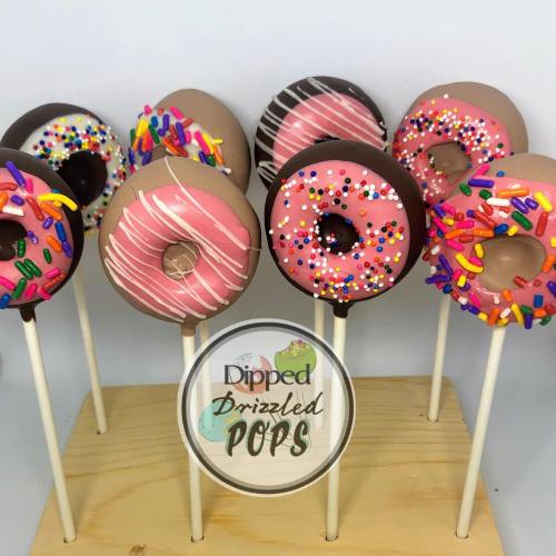 Colorful cake pops designed to look like donuts, displayed on sticks against a light background.