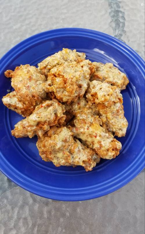 A blue plate filled with crispy, golden-brown chicken wings coated in a creamy sauce.