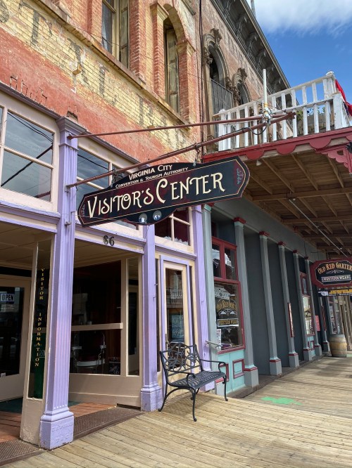 Sign for the Visitor's Center in Virginia City, featuring a colorful facade and wooden boardwalk.
