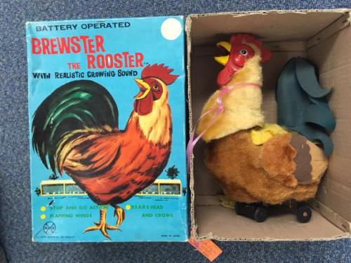 A vintage toy rooster named Brewster, with a colorful box and a plush body on wheels, featuring a crowing sound.