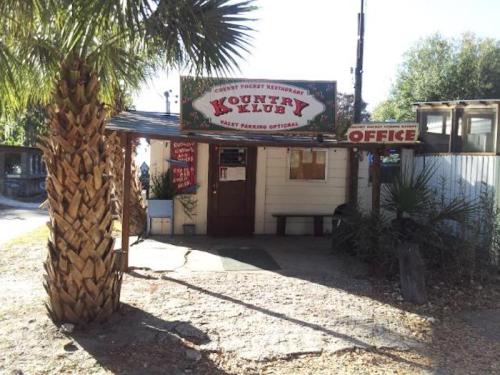 A rustic restaurant entrance with a sign reading "Kountry Klub" and palm trees in the foreground.