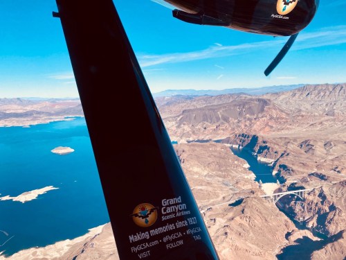 Aerial view of the Grand Canyon with a helicopter rotor blade in the foreground, showcasing the landscape below.