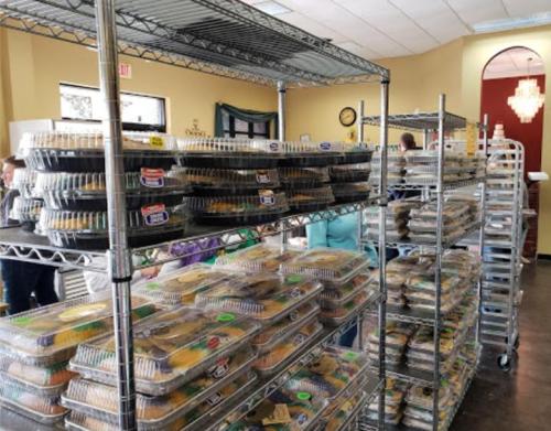 Shelves filled with stacked food containers in a bright, spacious room, with people in the background.