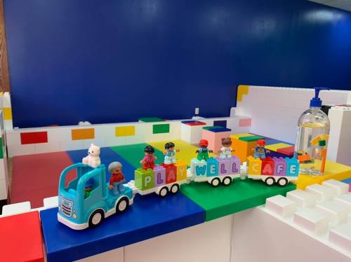 A colorful toy truck with figures on a train, set against a vibrant play area with building blocks.