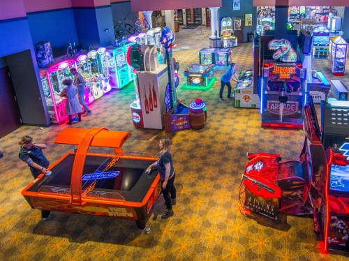 A vibrant arcade filled with various games and colorful lights, with people playing and interacting with the machines.
