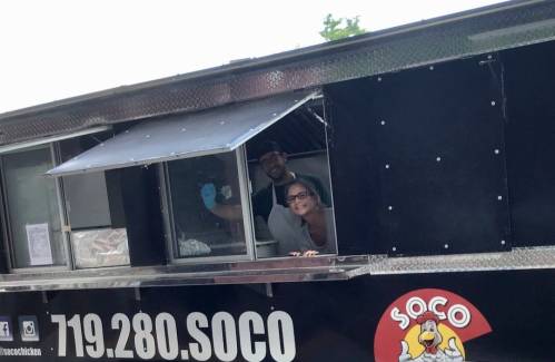A food truck with two smiling staff members at the service window, ready to serve customers.