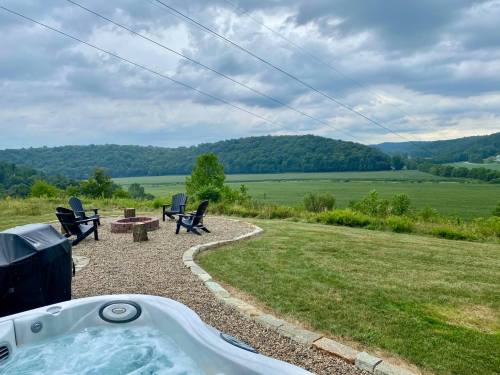 A scenic view of rolling hills and fields, with a hot tub and outdoor seating area in the foreground.