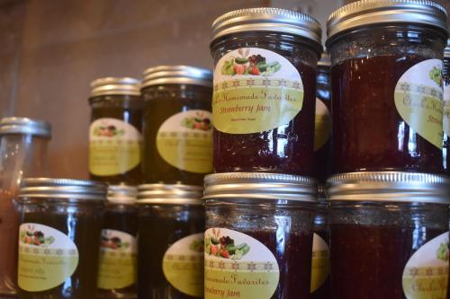 Jars of homemade strawberry jam with colorful labels, stacked on a shelf.