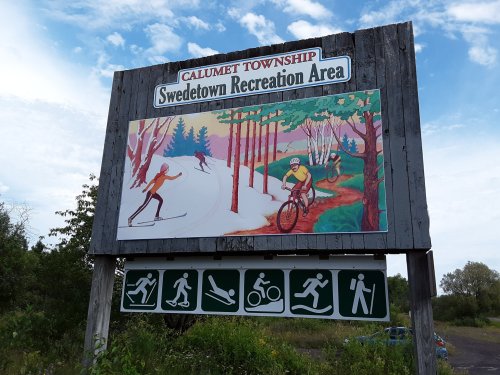 Sign for Swedetown Recreation Area in Calumet Township, featuring outdoor activities like skiing and biking.