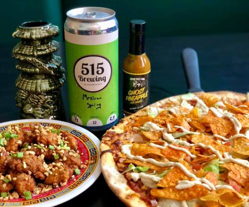 A vibrant spread featuring nachos, a pizza topped with chips, a can of beer, hot sauce, and decorative figurines.