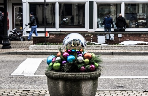 A decorative planter with colorful ornaments and a reflective sphere, set against a city street backdrop.