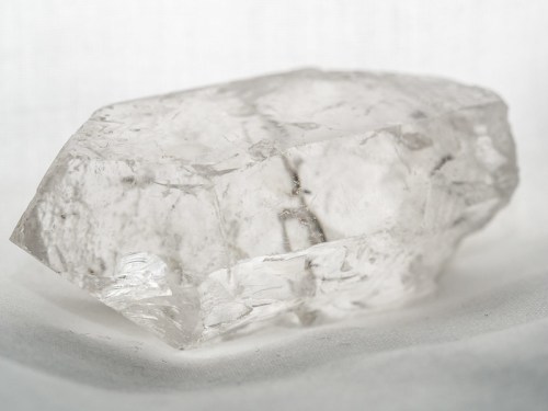 A clear, translucent crystal with sharp edges resting on a light background.