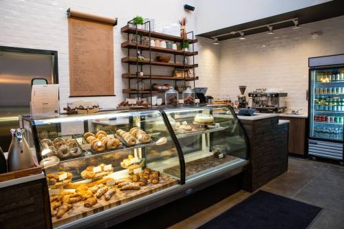 A cozy bakery display with various pastries and baked goods, featuring a glass case and a coffee station in the background.