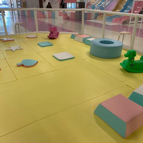 Colorful play area with soft mats, shapes, and a small slide, designed for children's activities and play.