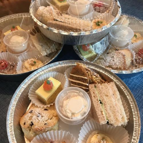Three trays of assorted desserts and sandwiches, each with small containers of cream and garnishes.