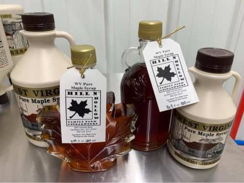 Three bottles of West Virginia pure maple syrup, featuring a leaf-shaped bottle and two traditional jugs with labels.