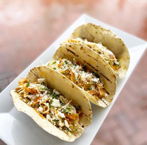 Three delicious tacos filled with colorful ingredients, served on a white plate.