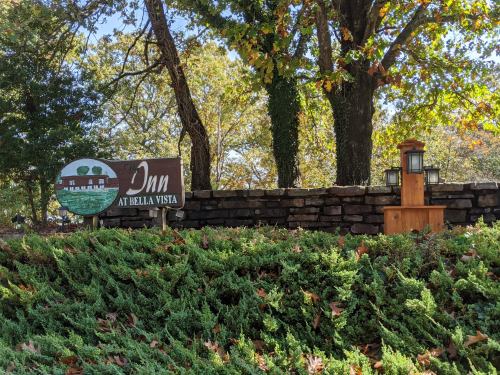 Sign for "Inn at Bella Vista" surrounded by greenery and trees, with decorative lanterns nearby.