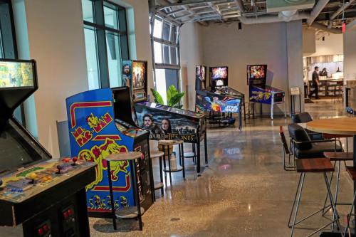 A row of vintage arcade machines in a modern space, with bright colors and a polished floor.