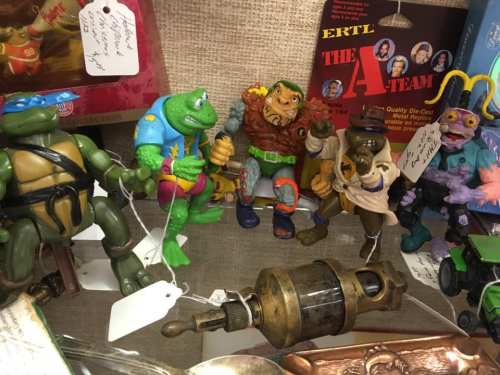 A collection of vintage action figures, including turtles and cartoon characters, displayed with price tags.