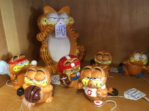 A collection of Garfield figurines in various sports poses, with a larger Garfield holding a sign in the center.