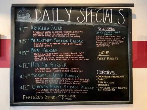 Chalkboard menu listing daily specials: salads, burgers, soup, and cupcakes with prices.