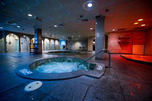 A spacious spa area featuring two hot tubs, tiled floors, and soft lighting, creating a relaxing atmosphere.