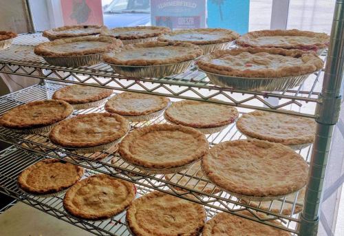A display of freshly baked pies cooling on wire racks in a bright shop window.