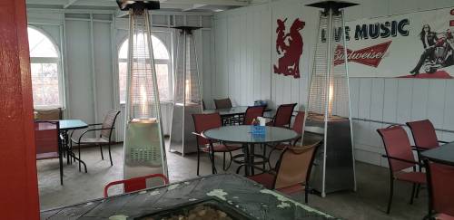 Indoor seating area with tables, chairs, and patio heaters, featuring a vintage music-themed wall decoration.