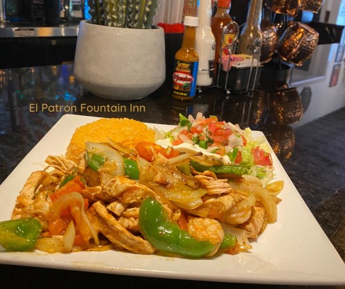 A plate of chicken fajitas with rice and a fresh salad, served at El Patron Fountain Inn.