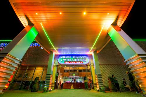 Brightly lit entrance of Jijeu Sauna Wellbeing, featuring colorful neon signs and a welcoming atmosphere.