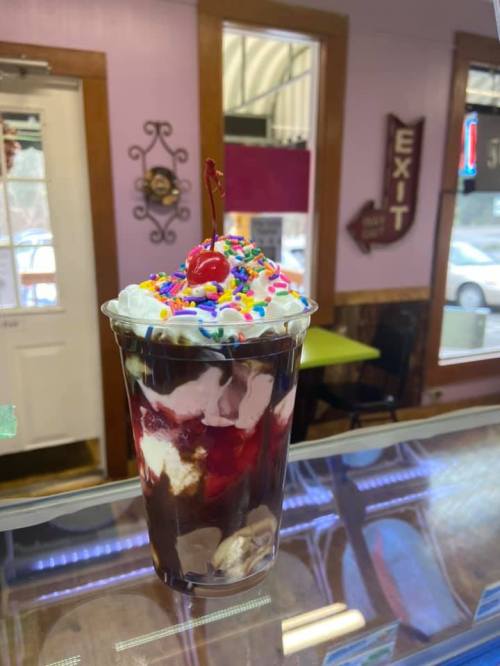 A delicious sundae in a clear cup, topped with whipped cream, a cherry, and colorful sprinkles.