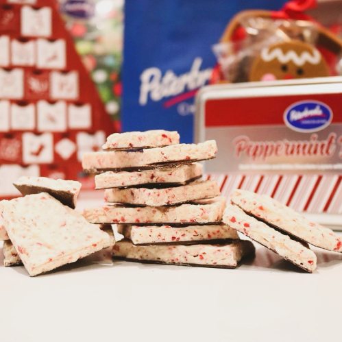 A stack of peppermint bark pieces with festive packaging in the background.