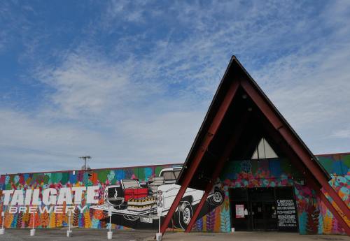 Colorful mural on a brewery building featuring a vintage truck, with a distinctive triangular roof design.