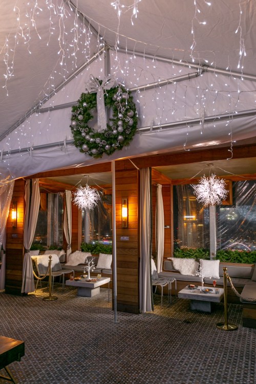 Cozy indoor space decorated with a wreath and fairy lights, featuring seating areas and festive decor.