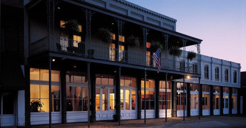 Historic building with balconies, large windows, and an American flag, illuminated at dusk.