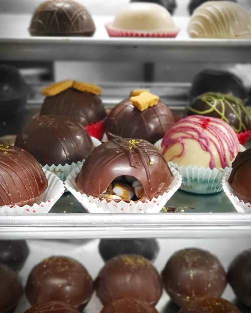 A variety of decorative chocolate truffles in a display case, featuring different colors and toppings.