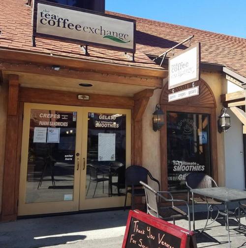Exterior of a café with signs for coffee, crepes, gelato, and smoothies. A thank you sign for veterans is in front.