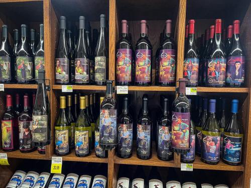 A display of various wine bottles on wooden shelves, featuring colorful labels and different types of wine.