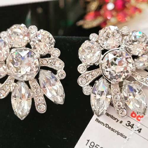 Close-up of sparkling vintage earrings featuring large and small clear rhinestones in a floral design.